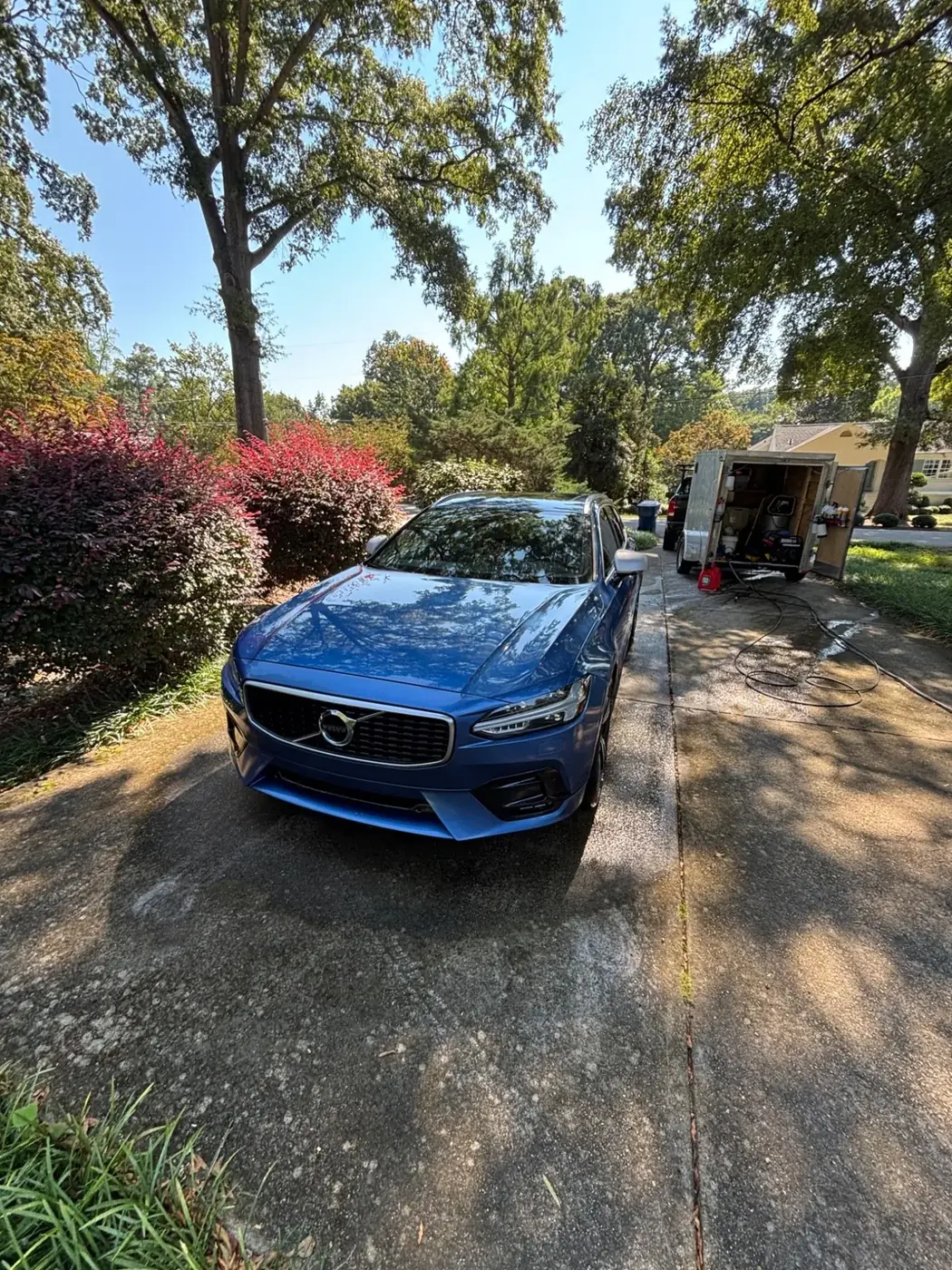 Finished blue Volvo beside the Road Bubbles mobile detailing trailer